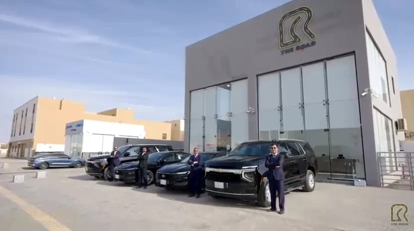 Road staff and vehicles outside a building displaying The Road logo